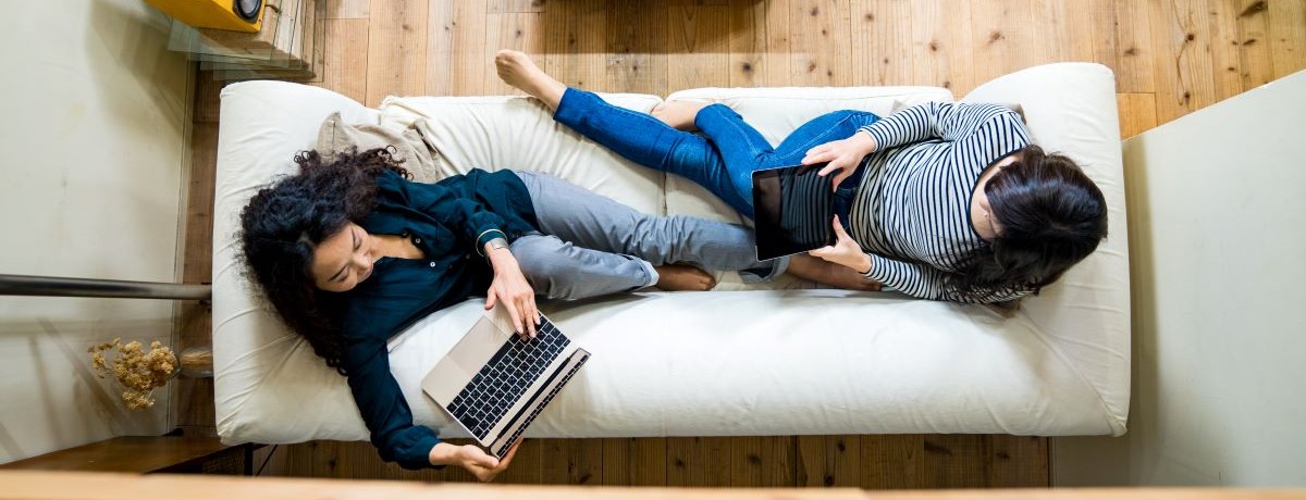 renters in their apartment laying on the sofa using smart devices